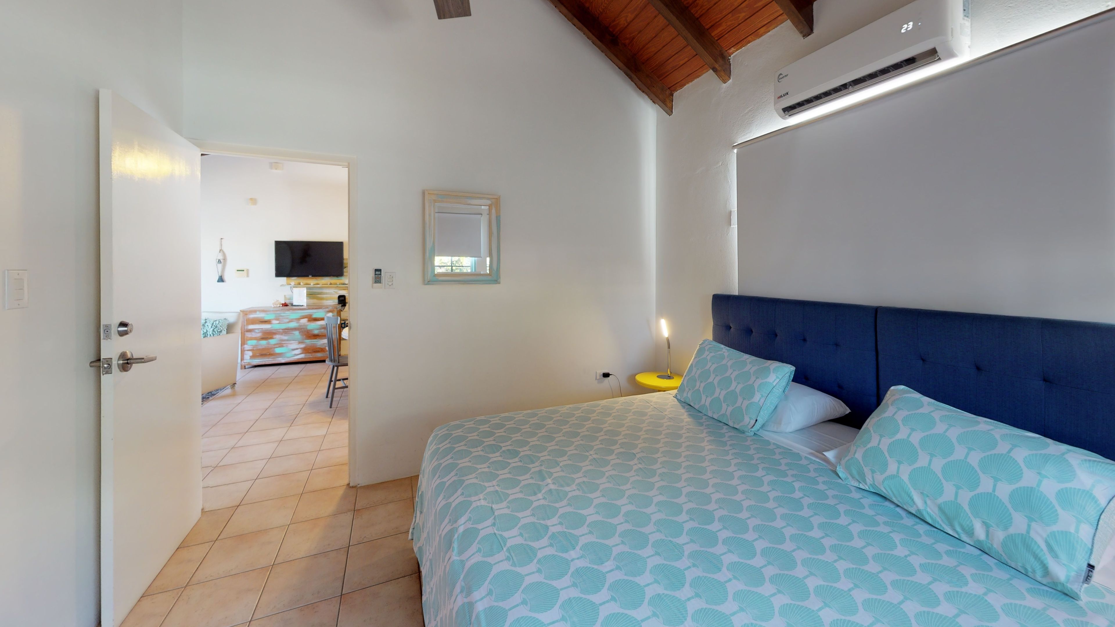 Ein Schlafzimmer mit Bett, Nachttisch und Fernseher im angrenzenden Raum.