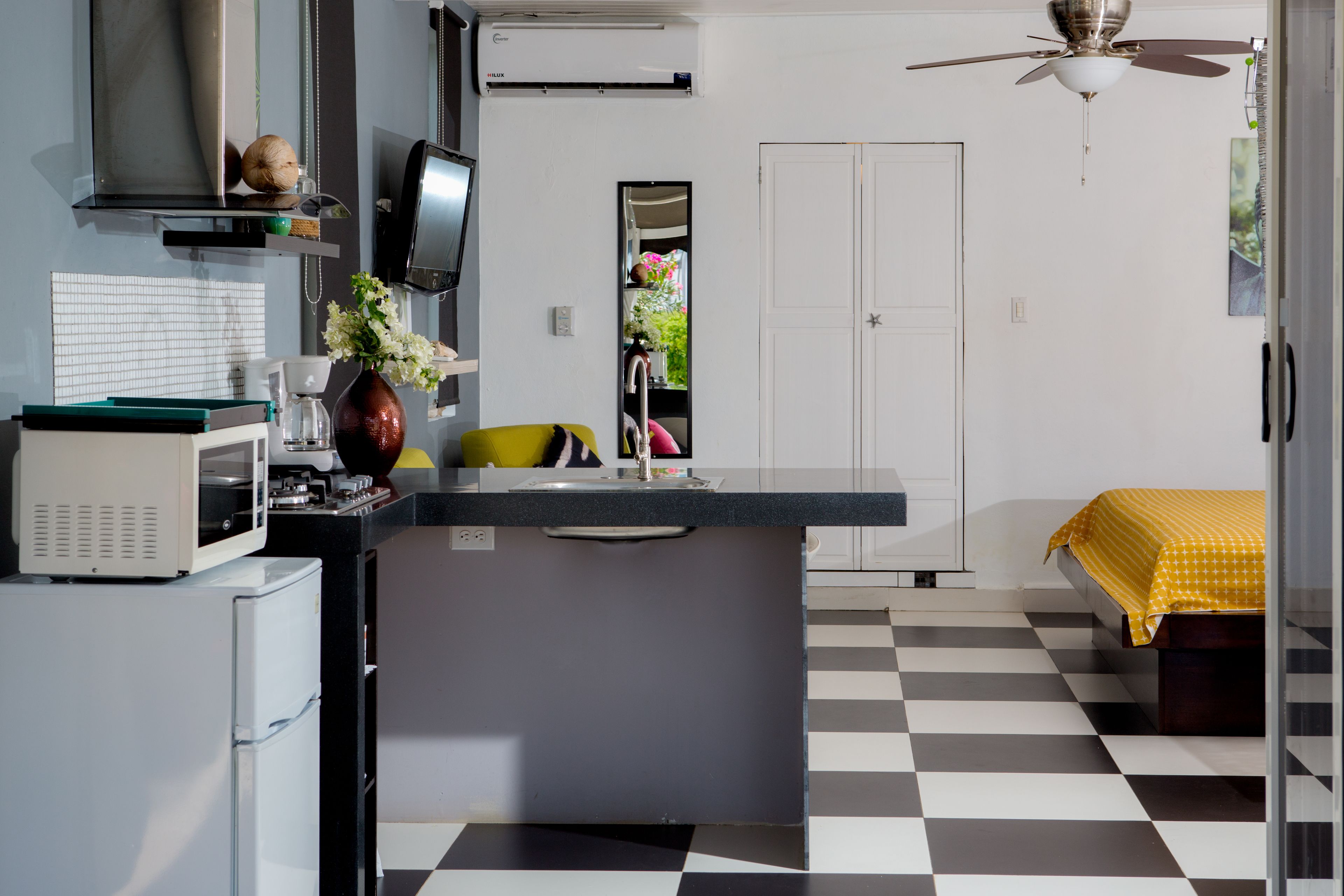A compact kitchen with a microwave, refrigerator, sink, and a ceiling fan.