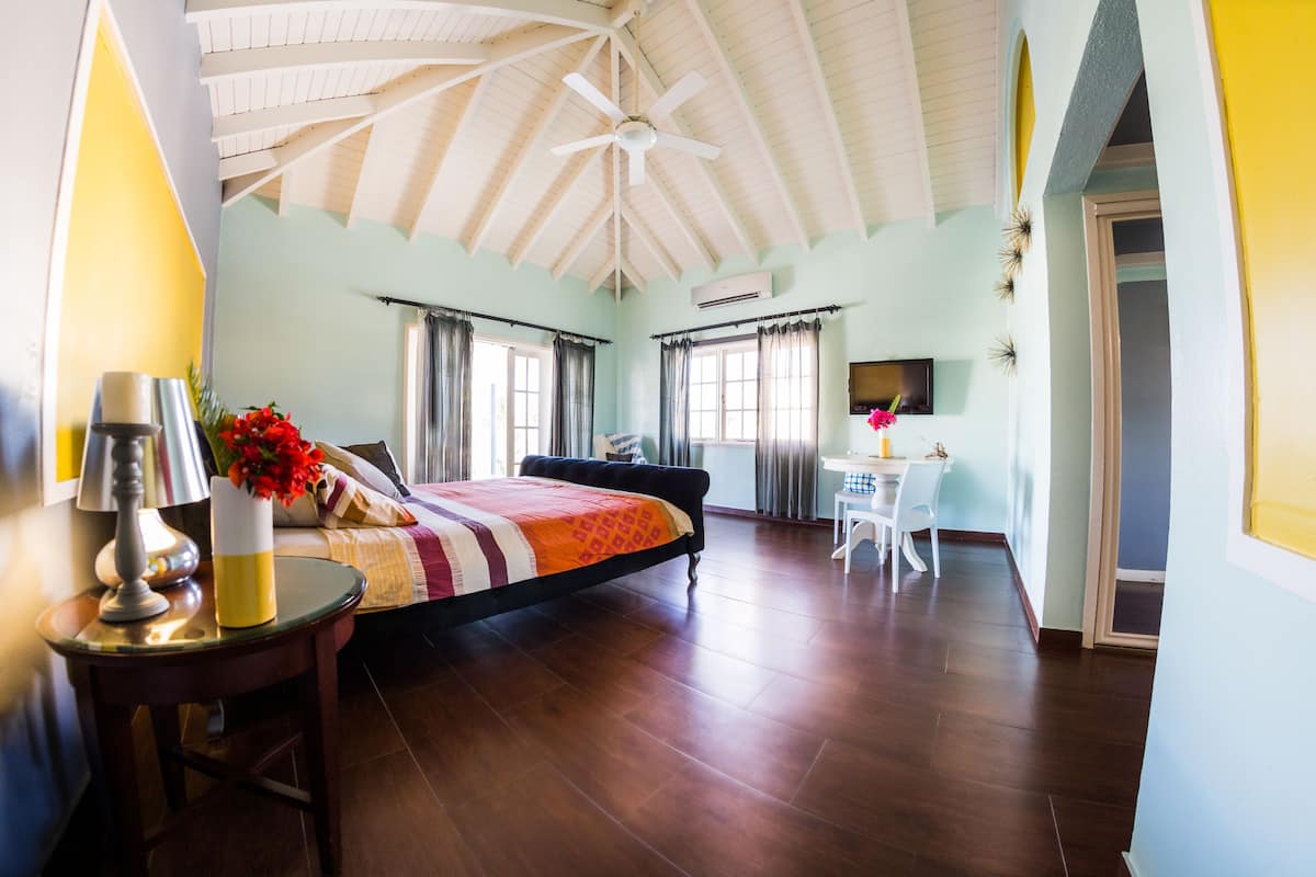 A bedroom with a bed, a desk, a chair, and a ceiling fan.