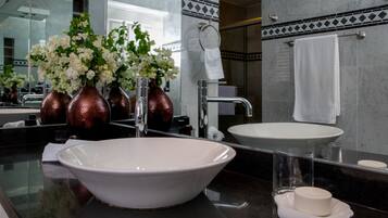 Un baño moderno con un lavamanos grande blanco, un espejo y un florero con flores blancas.
