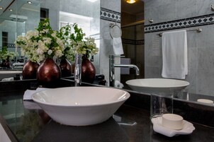 Un baño moderno con un lavamanos grande blanco, un espejo y un florero con flores blancas.