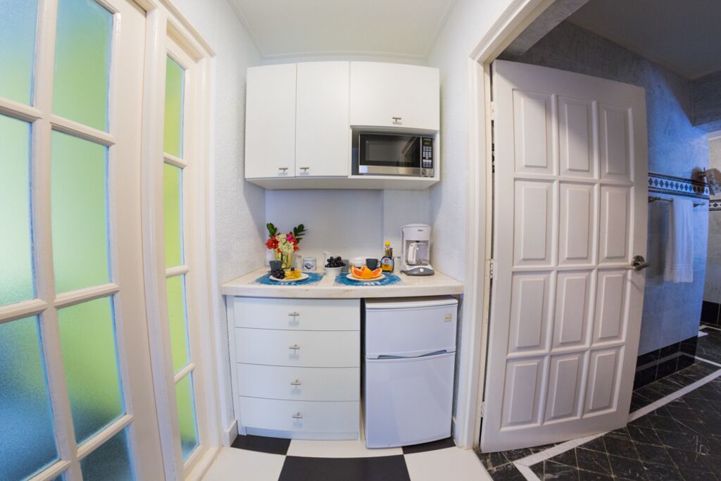 Cocina compacta equipada con microondas, cafetera y refrigerador.