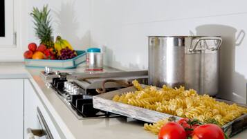 Una encimera de cocina con pasta, tomates y una olla.