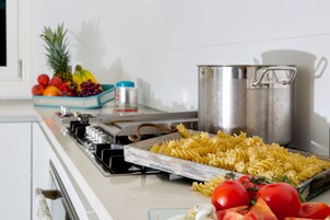 Una encimera de cocina con pasta, tomates y una olla.