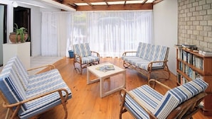 A room with four striped armchairs, a coffee table, and a bookshelf. - Greystone Guest House (Jeffreys Bay)