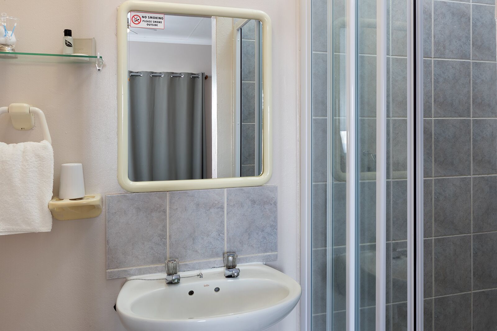 A bathroom with a sink, mirror, and shower area.