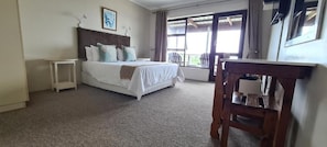 A bedroom with a bed, a small table, and a chair. - Greystone Guesthouse (Jeffreys Bay)