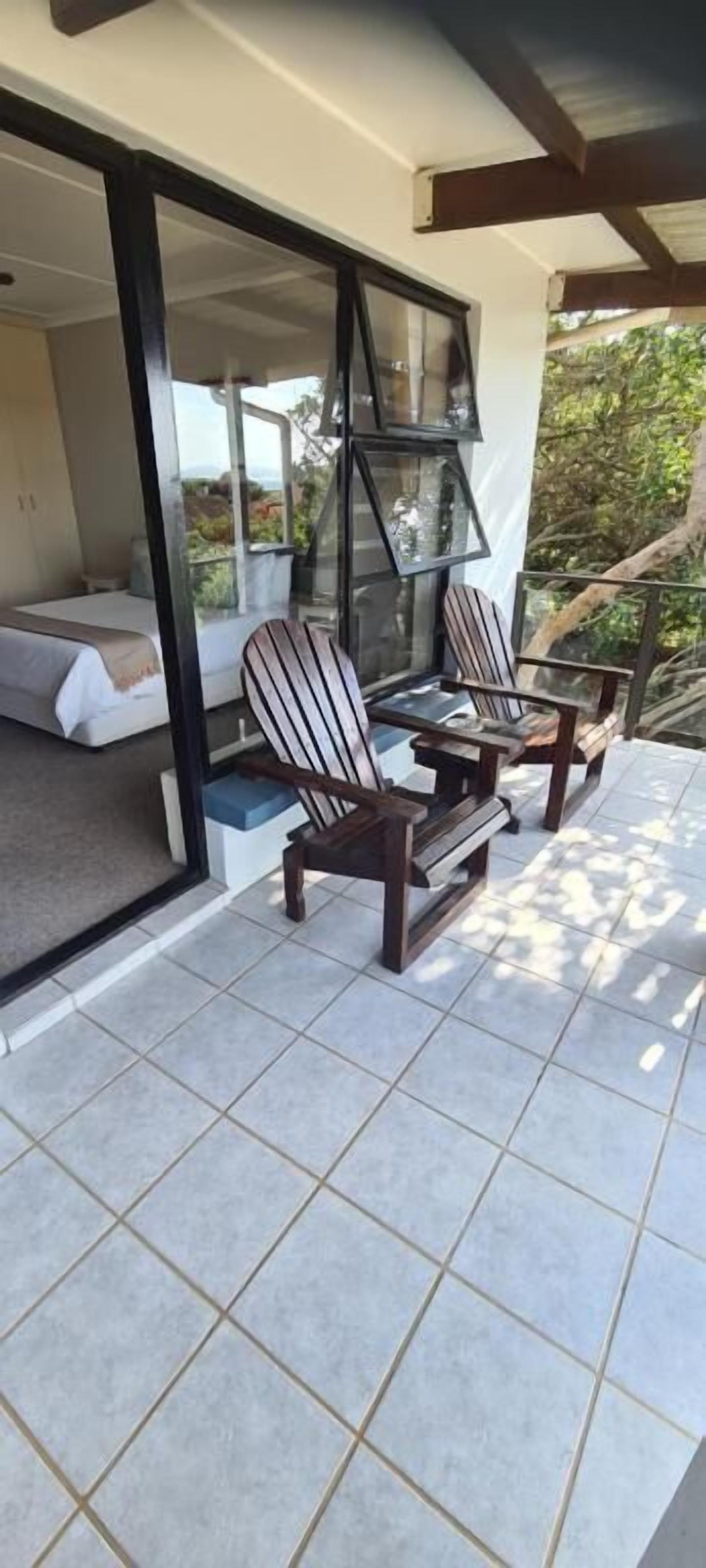 A balcony with a bed, two chairs, and a table.