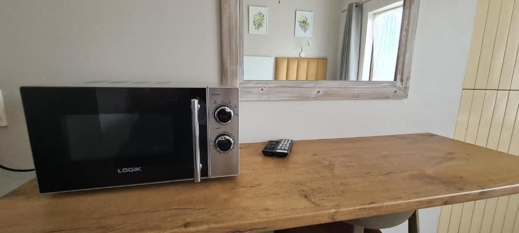 Un four à micro-ondes posé sur une table en bois, avec une télécommande à côté.