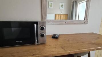 Een magnetron op een houten tafel, met een afstandsbediening ernaast.