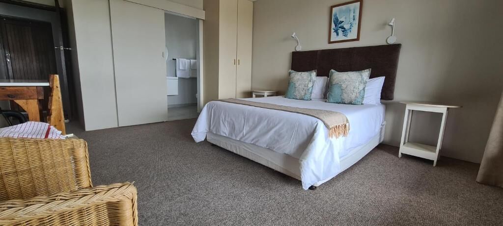 A hotel room with a bed, a small bedside table, a chair, and a wardrobe.