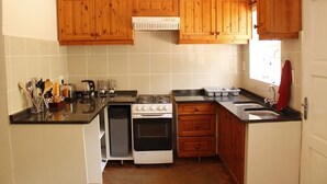 A compact kitchen with wooden cabinets, a stove, a dishwasher, and a sink. - Magoebaskloof Getaway (Tzaneen)