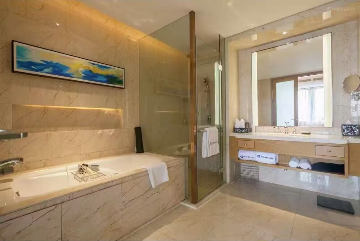 A modern bathroom with a glass-enclosed shower, a large mirror, and a marble sink.