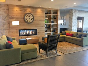 A modern living room with a fireplace, sofas, a bookshelf, and a clock on the wall.