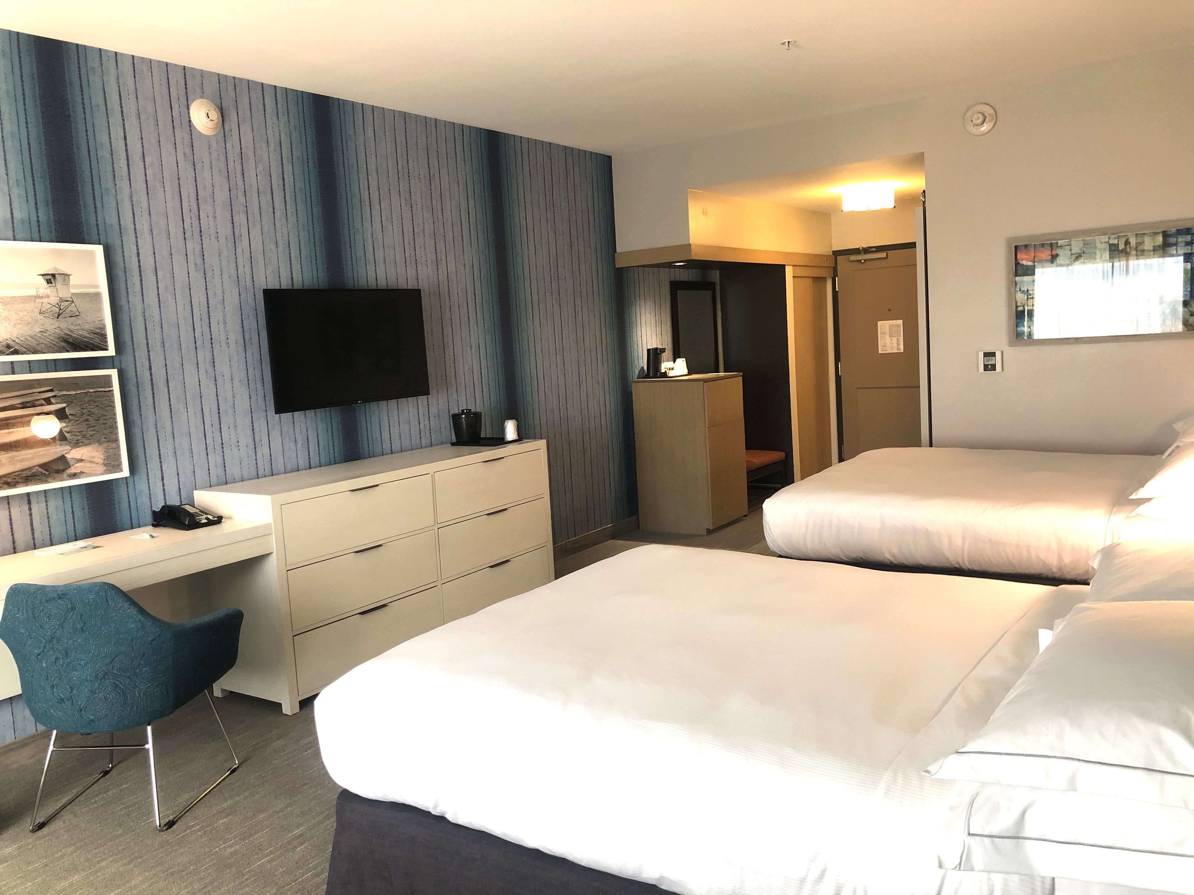 Habitación de hotel con dos camas, un escritorio, una silla, un televisor y un armario.