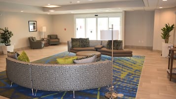 A modern lounge area with a patterned seating arrangement, a coffee table, and a floor lamp.