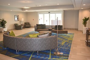 A modern lounge area with a patterned seating arrangement, a coffee table, and a floor lamp.