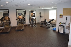 Un gimnasio con cintas de correr, elípticas y equipo de pesas.