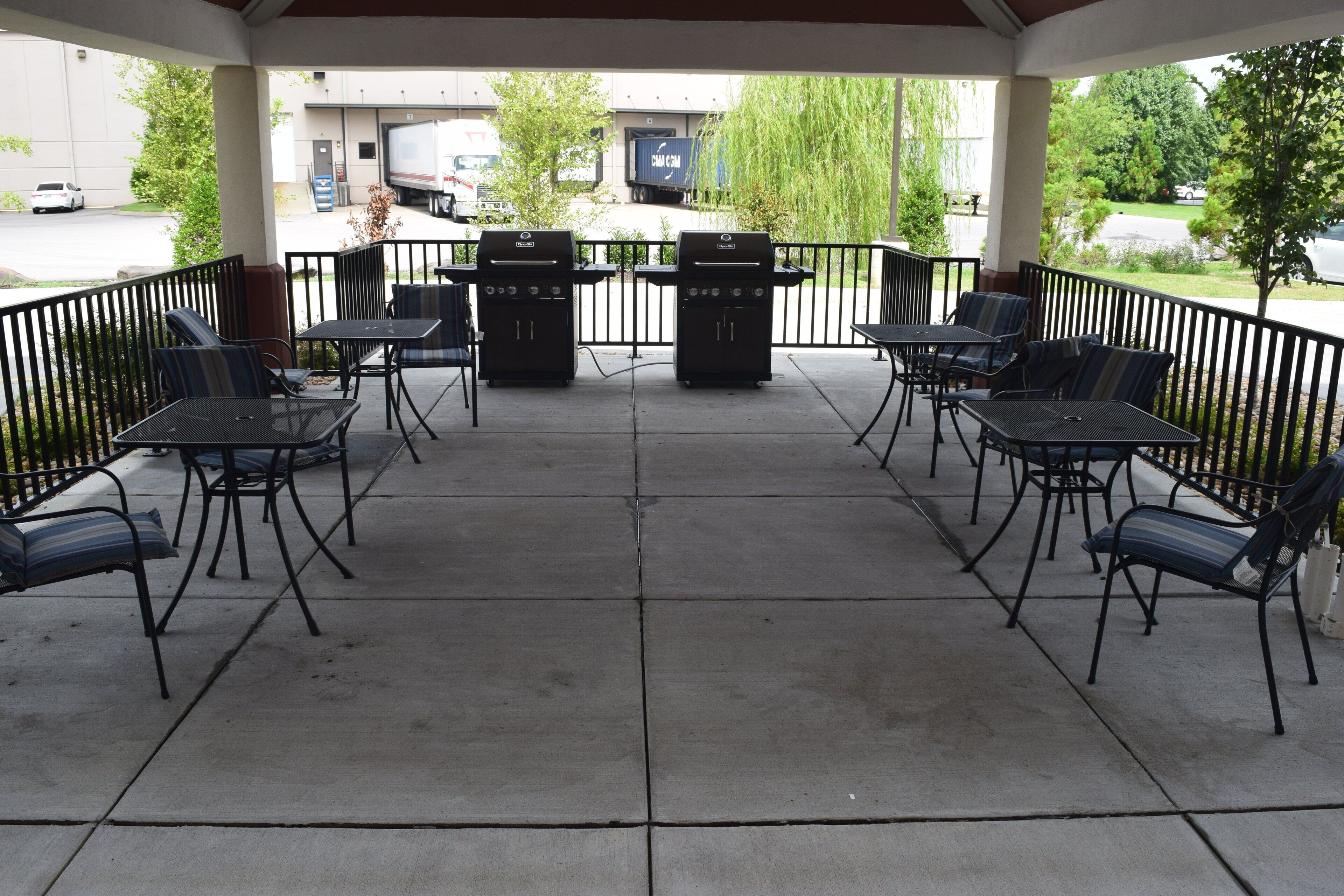 An outdoor patio with a grill, seating, and a view of the street.