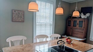 A kitchen with a granite countertop, white cabinets, a built-in stove, and pendant lighting. - Bristol Suites (Bristol)