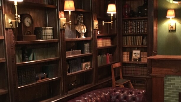 A library with leather sofas, bookshelves, and wall-mounted lamps. - Bristol Suites (Bristol)