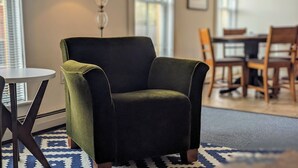 A green armchair in a room with a patterned rug, a table, and a lamp. - Bristol Suites (Bristol)