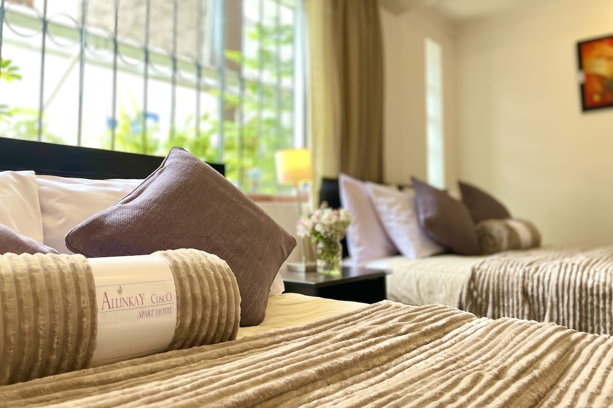 A hotel room with a bed, pillows, and a window with a view of greenery.