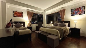 A hotel room with two beds, a desk, and a chair. There are two windows with curtains, a painting on the wall, and a lamp on the desk. - Allinkay Cusco Apart Hotel (Cusco)