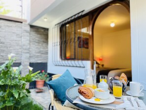 A breakfast setup with croissants, eggs, and orange juice on a table outside a building with a stone wall and a window with metal bars. - Allinkay Cusco Apart Hotel (Cusco)