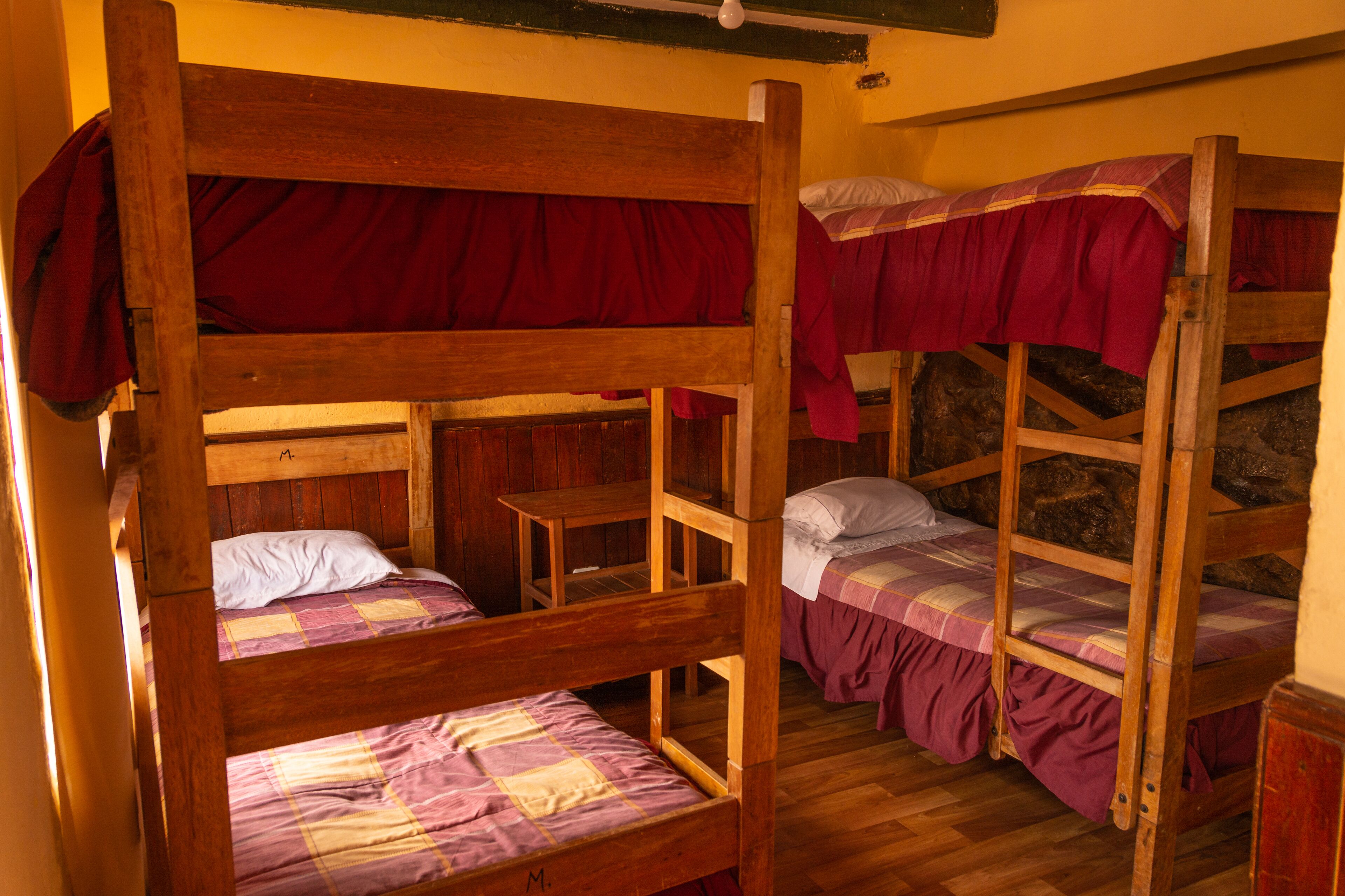 A bunk bed room with wooden frames and red bedding.
