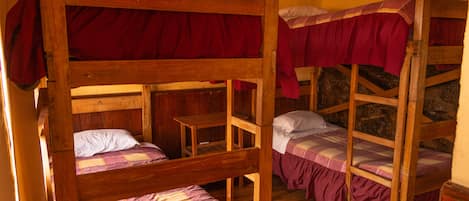 Quarto com beliches de madeira e roupa de cama vermelha.
