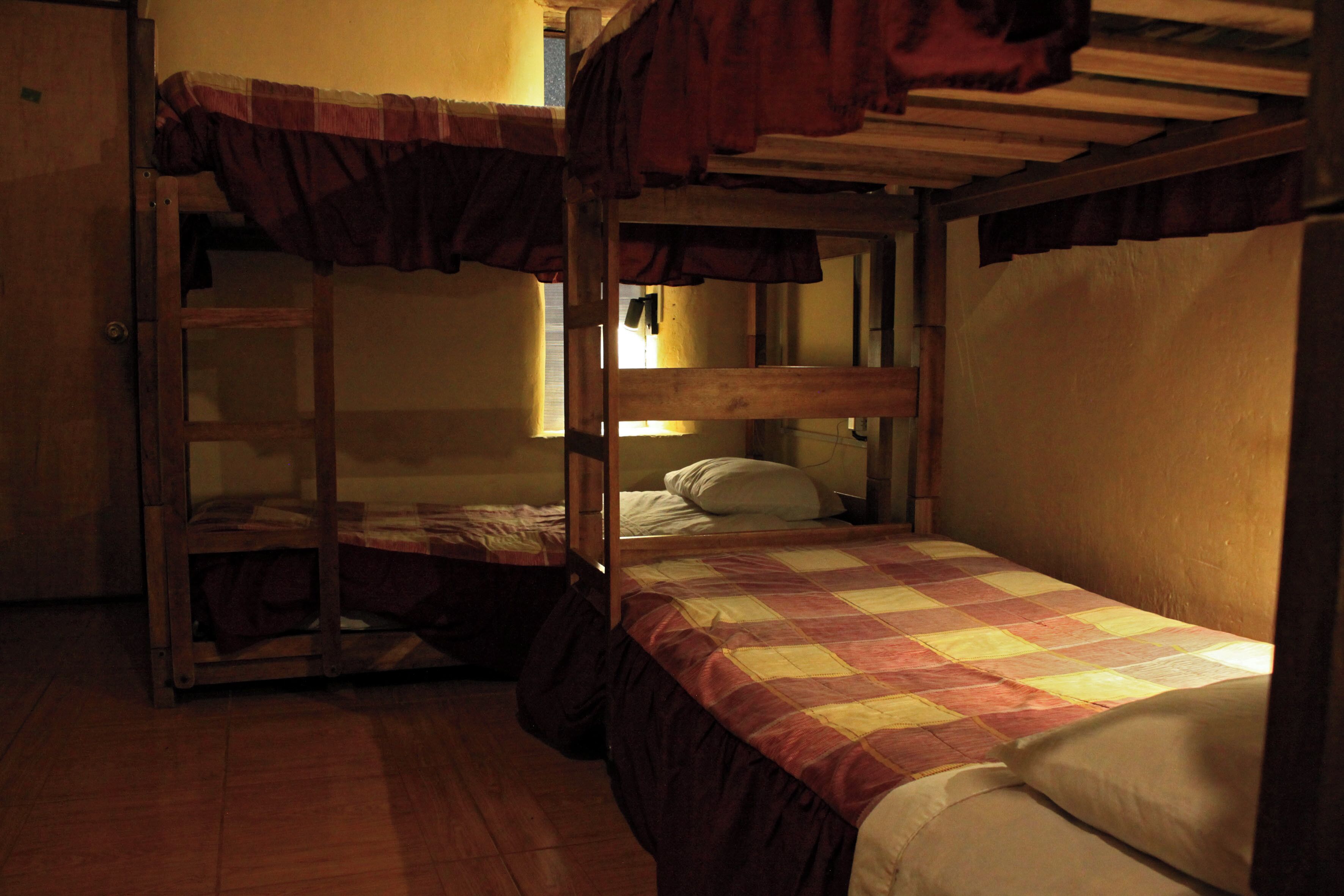 A bunk bed room with a checkered bedspread and wooden bunk beds.