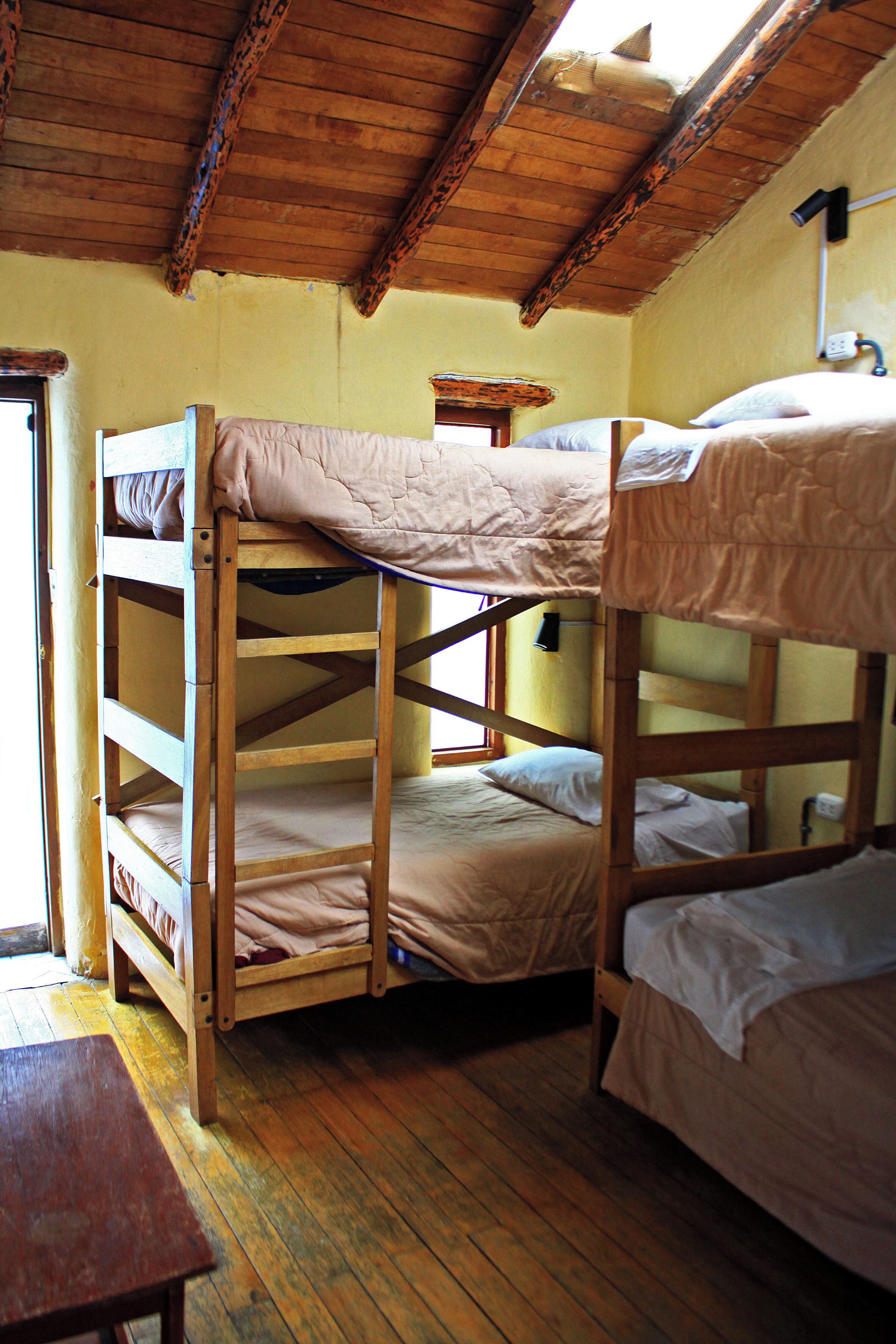 A bunk bed room with wooden beams and a window.