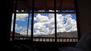 A room with a large window overlooking a mountainous landscape with clouds. - Samay Wasi Youth Hostel (Cusco)