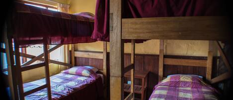Camera con letti a castello, strutture in legno e biancheria viola.