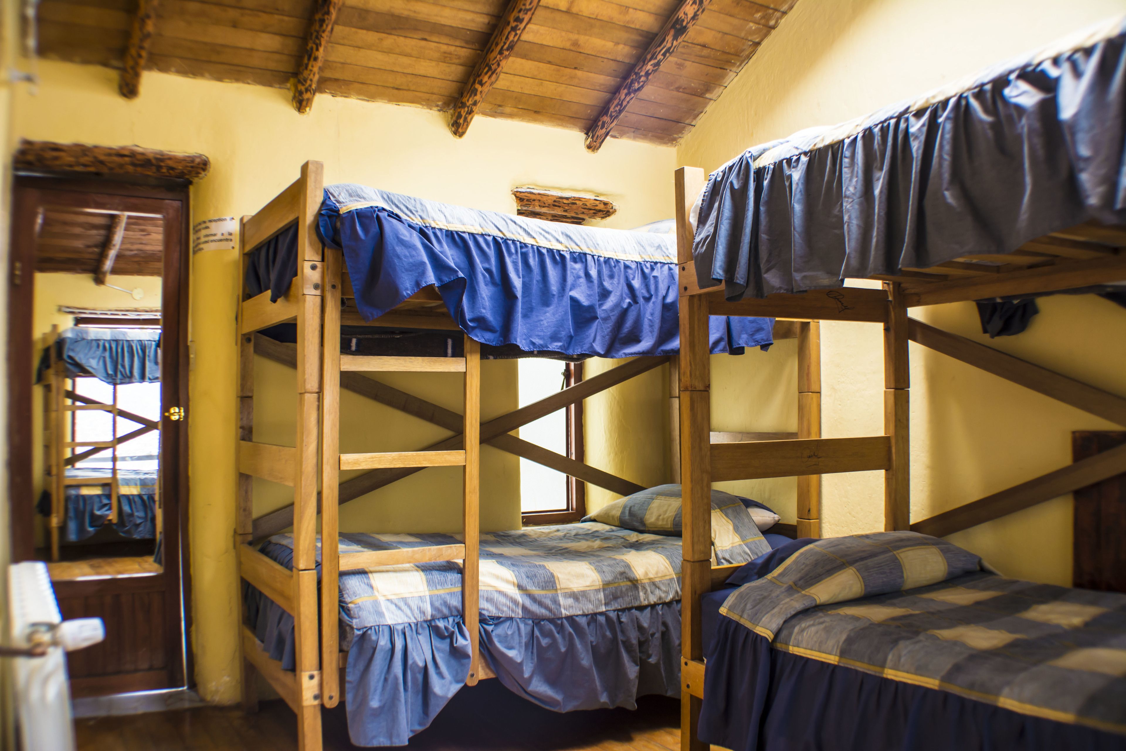 Une chambre de dortoir avec des lits superposés, des poutres en bois et une fenêtre.