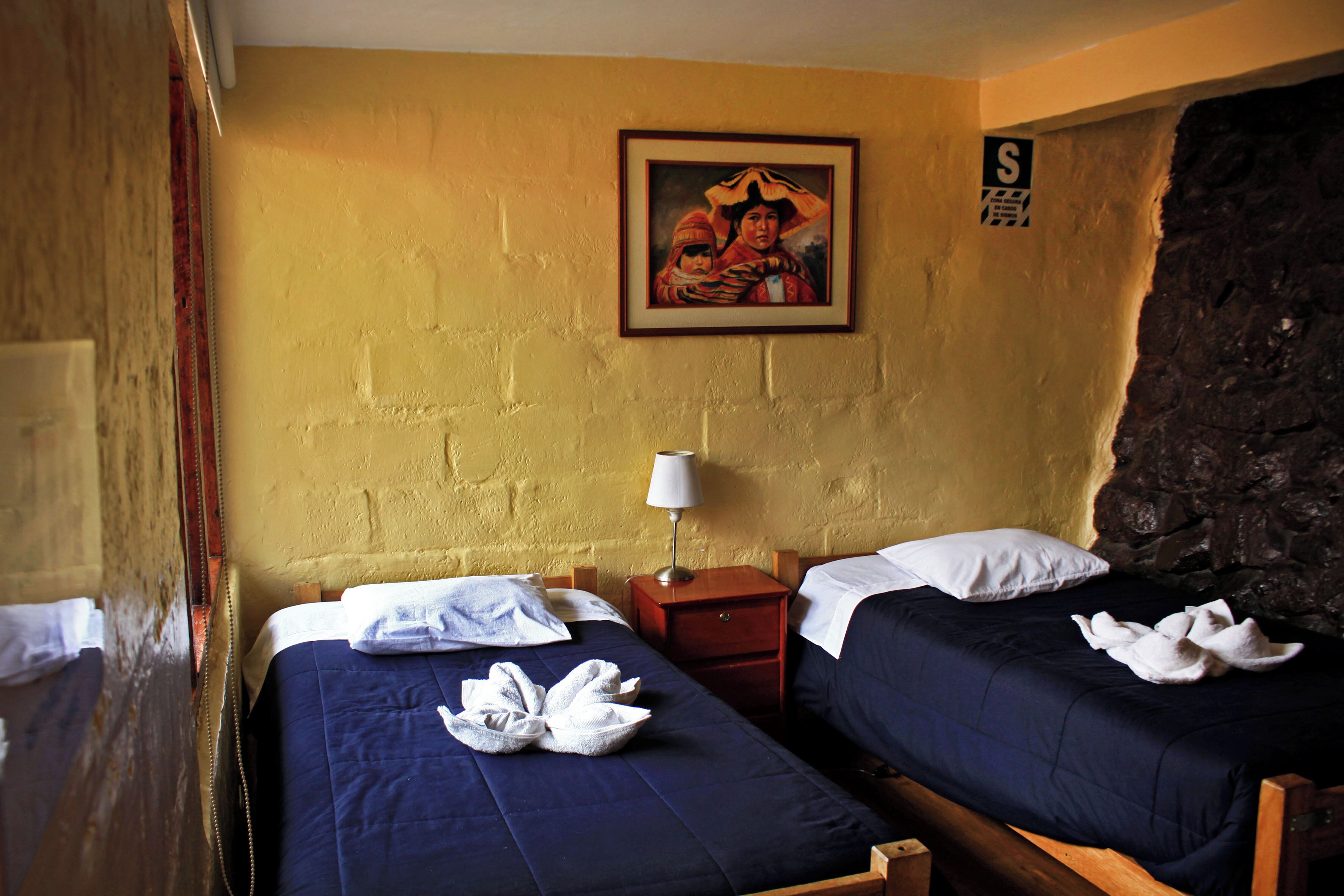 A room with two beds, a painting on the wall, and a sign with an 'S'.