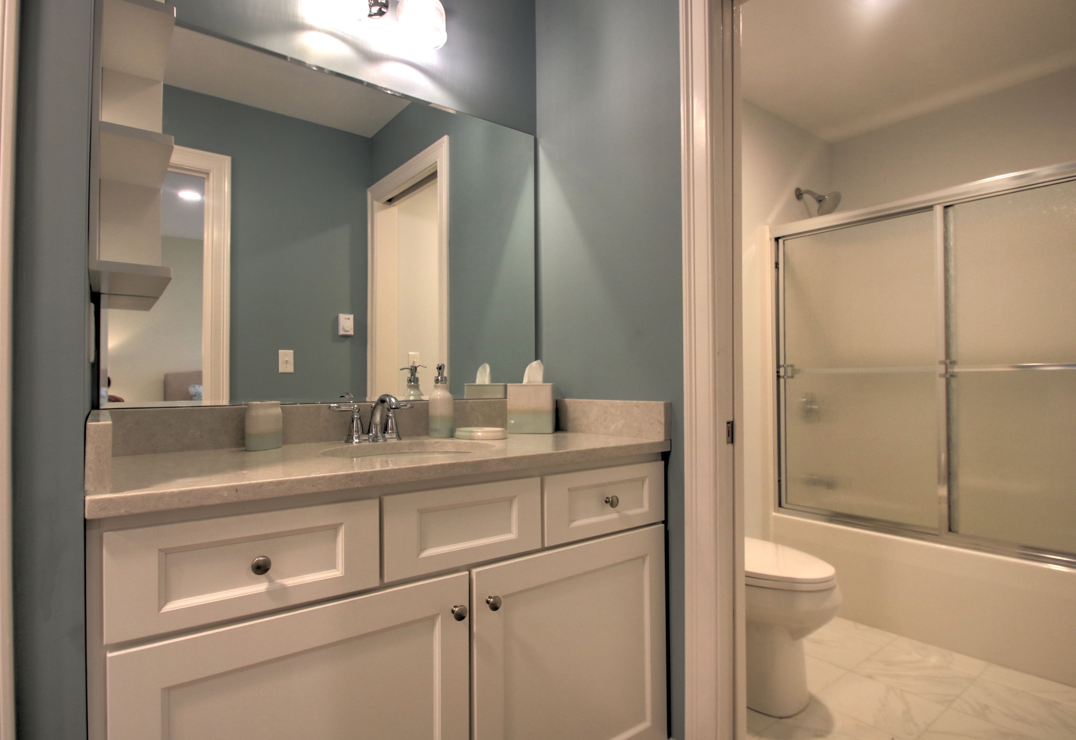A bathroom with a white sink, mirror, and toilet.