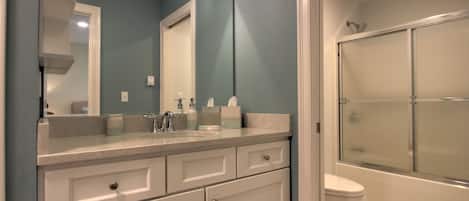 A bathroom with a white sink, mirror, and toilet.