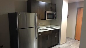 A compact kitchen with a stainless steel refrigerator, a microwave, and a sink. - Super 8 by Wyndham Pascagoula (Pascagoula)
