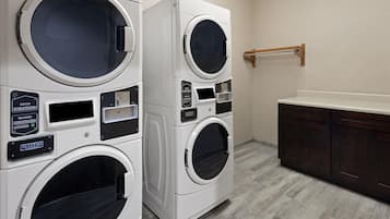 A laundry area with two stacked washing machines and a wooden drying rack.