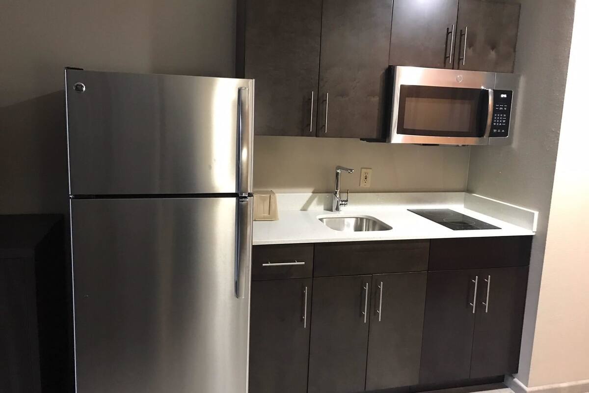 A kitchen with stainless steel appliances, a double sink, and dark cabinetry.