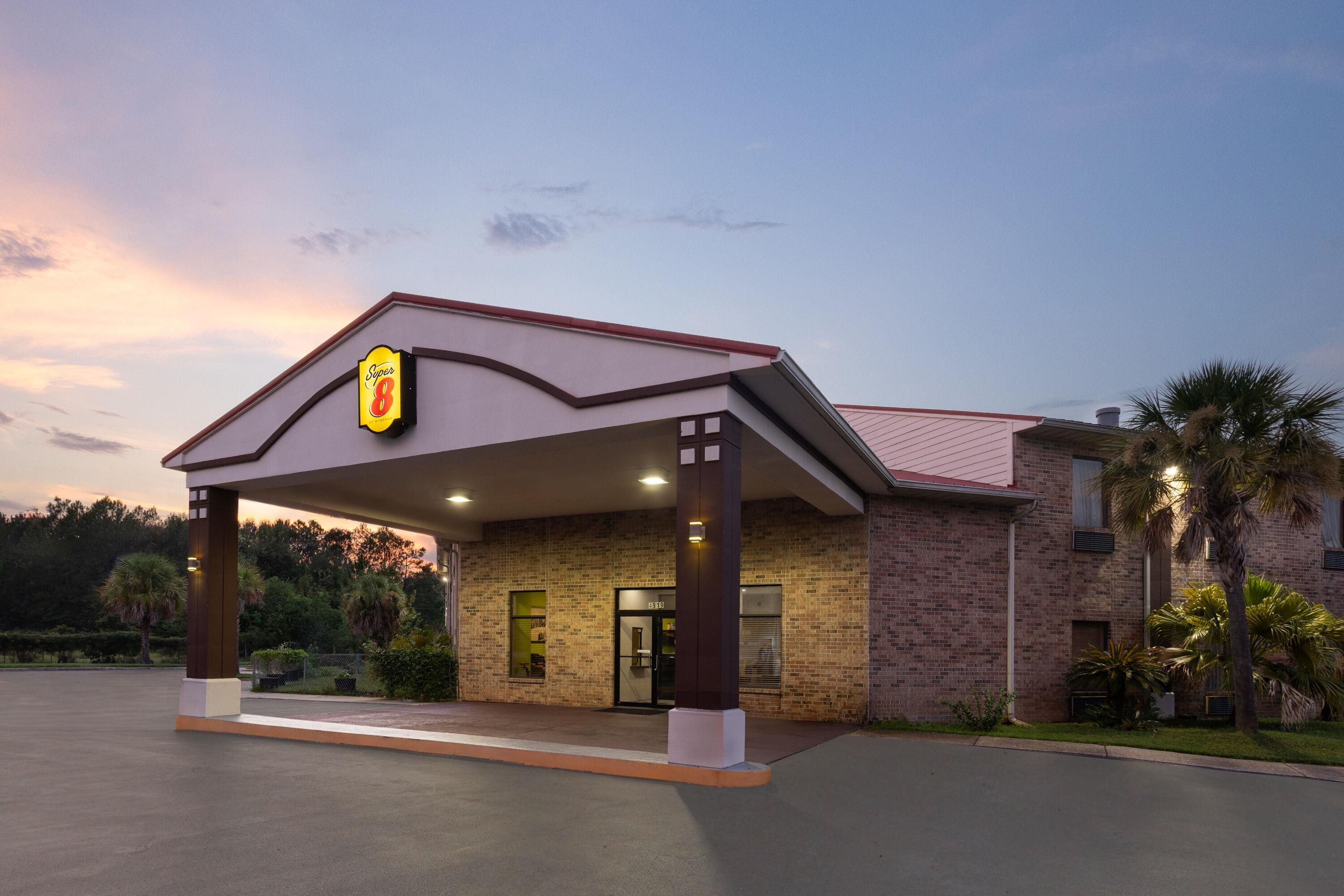 Un hotel con fachada de ladrillo, un acceso cubierto y un letrero que indica que es un Super 8.
