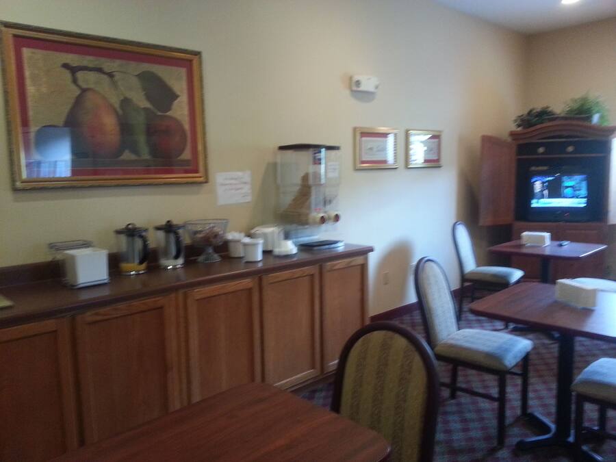 Un comedor con mesas y sillas de madera, una estación de café y un televisor sobre un mueble.
