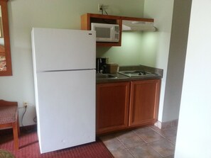 A compact kitchen with a white refrigerator, a microwave, and a stove. - Super 8 by Wyndham Pascagoula (Pascagoula)