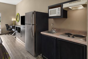 Una cocina funcional con refrigerador, microondas, fregadero y estufa.