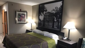 A hotel room with a bed, two bedside tables with lamps, a framed picture on the wall, and a door. - Super 8 by Wyndham Pascagoula (Pascagoula)
