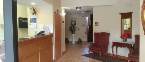 A reception area with a wooden desk, a reception phone, a clock, and a sign indicating the lobby.