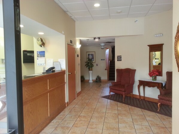 A reception area with a wooden desk, a reception phone, a clock, and a sign indicating the lobby. - Super 8 by Wyndham Pascagoula (Pascagoula)