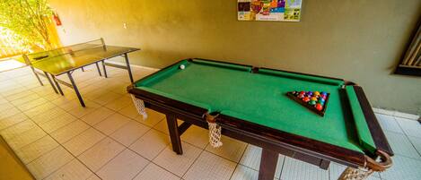 A pool table with a green felt surface and a set of billiard balls.